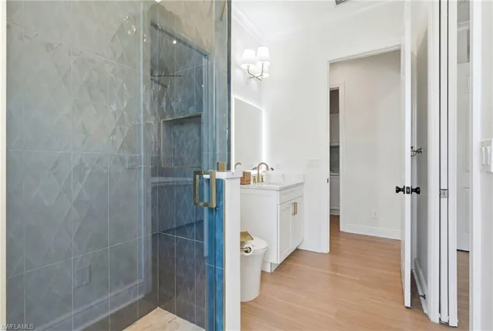 Glass-enclosed shower with textured tile surround and recessed shelving