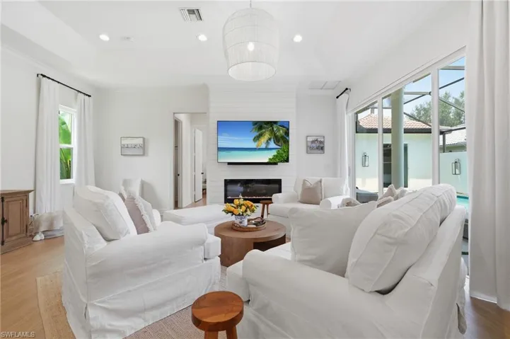 Spacious living area featuring light wood-finish flooring, recessed lighting, and a linear fireplace with shiplap accent wall