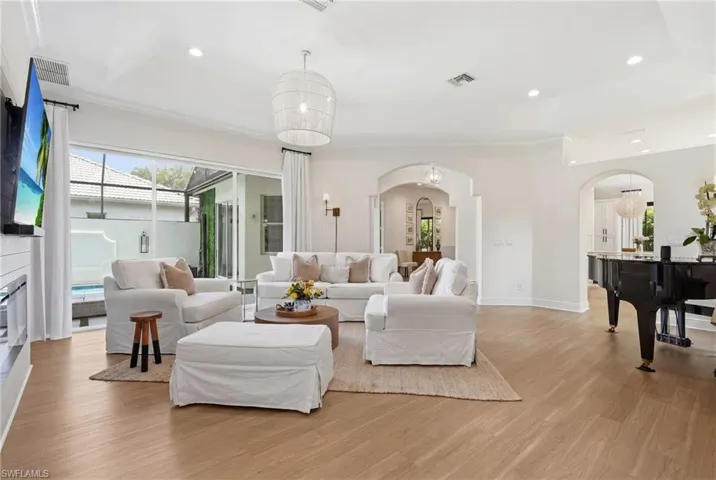 Spacious living area featuring wood-finish flooring, vaulted ceilings, and extensive sliding glass doors