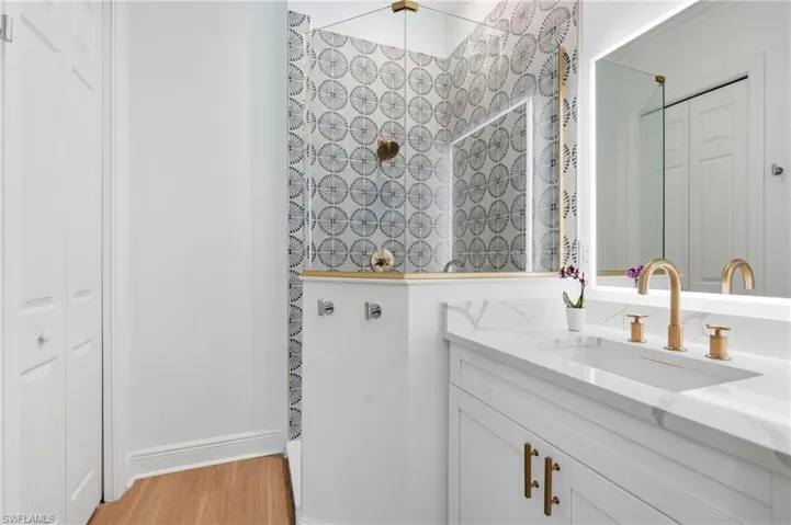 Bathroom featuring a white vanity with gold-finish hardware, a single undermount sink, and a white countertop