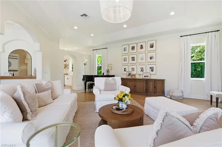 Spacious living area featuring light wood-finish flooring and multiple windows with outdoor greenery