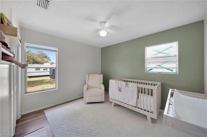Bedroom 2 with a textured ceiling, a ceiling fan, visible vents, wood finished floors, space for a crib as shown, or make it your own bedroom.