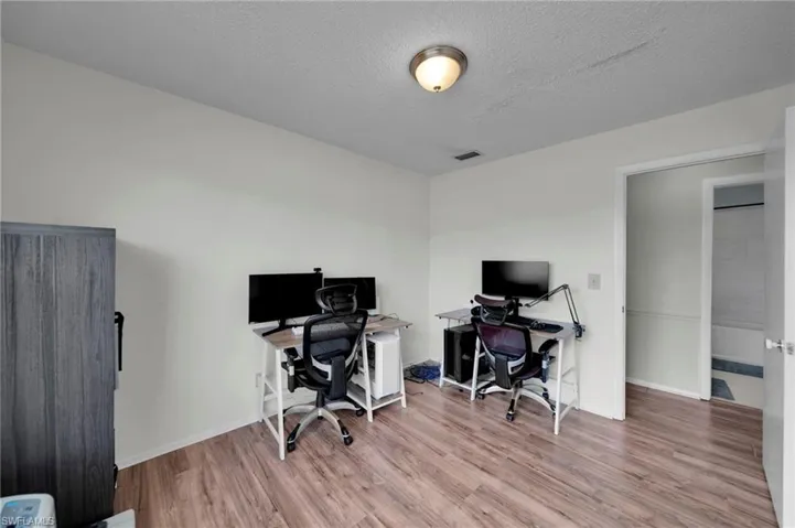 Home office/ Bedroom/ storage room 3-with Vinyl Wood floors, baseboards, visible vents, and a textured ceiling