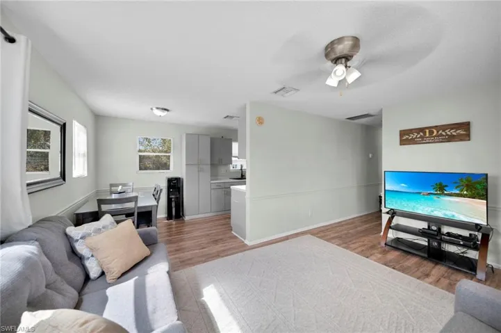 Living room with visible vents, ceiling fan, wood finished floors, and baseboards