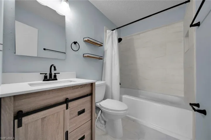 Full bath with shower / NEW bathtub combination with curtain, NEW vanity, a textured ceiling, and toilet