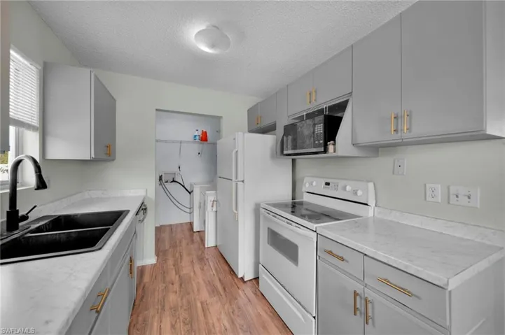 Kitchen with a NEW sink, New Laminate countertops, electric stove, Vinyl Wood finished floors, and gray cabinets, gold hardware.