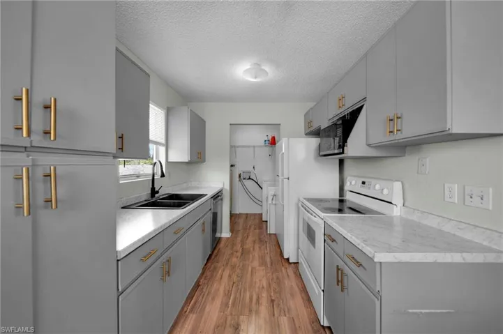 Kitchen with a NEW sink, New Laminate countertops, electric stove, Vinyl Wood finished floors, and gray cabinets, gold hardware.