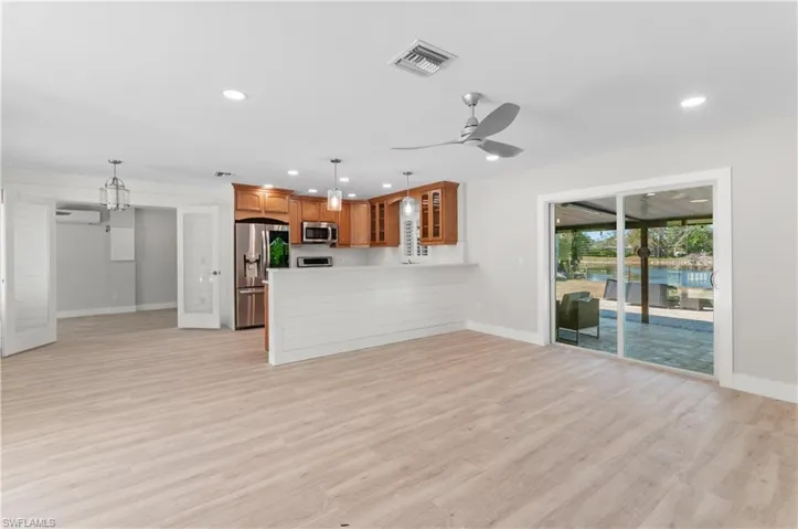 Unfurnished living room with light wood-type flooring, ceiling fan, and hanging lights