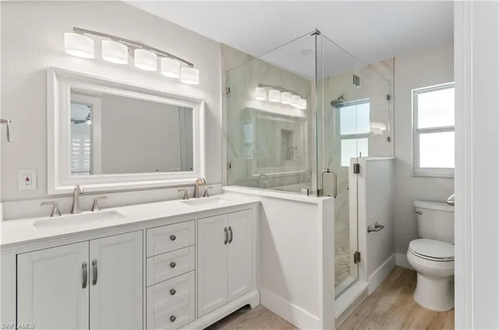 Bathroom#1  featuring double vanity, a marble finish shower, and light wood-style floors