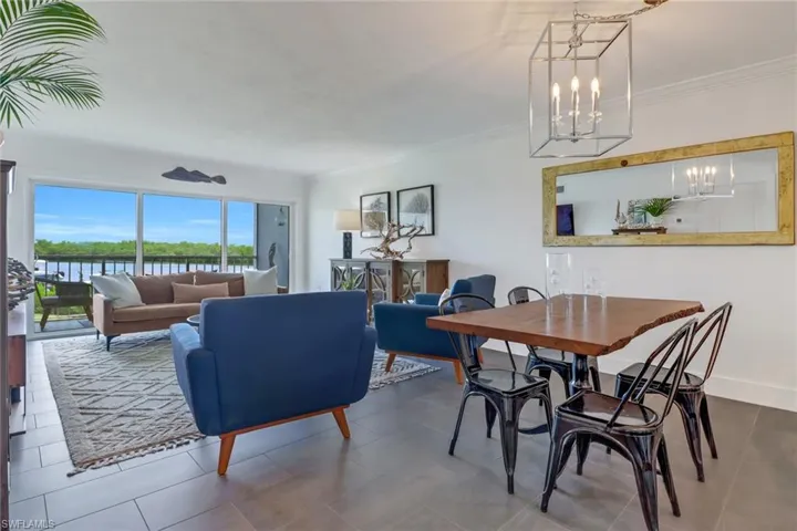 Dining space featuring a water view, tile patterned flooring, crown molding, and a notable chandelier