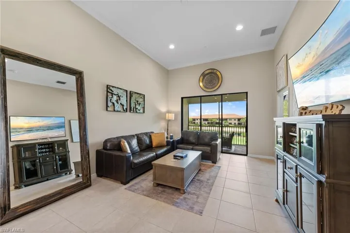 Spacious living area featuring high vaulted ceilings and light-toned tile flooring