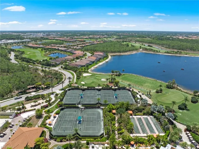 Aerial perspective showcasing multiple tennis courts, bocce ball courts, a golf course, and a large lake