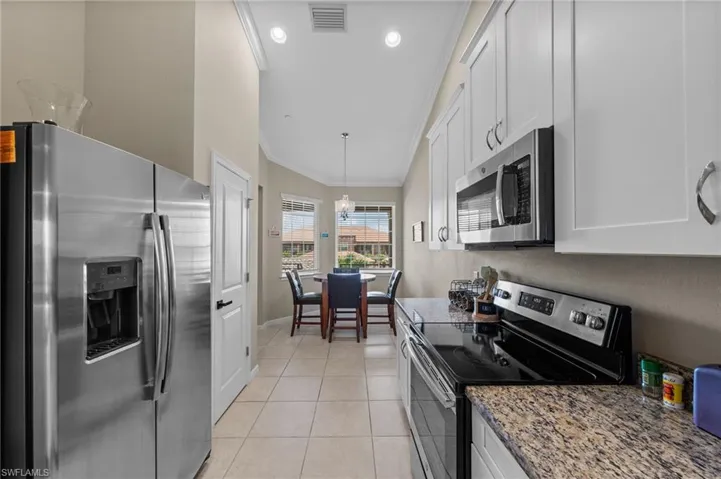 Kitchen featuring stainless steel appliances, white cabinetry, granite-finish countertops, and tile flooring