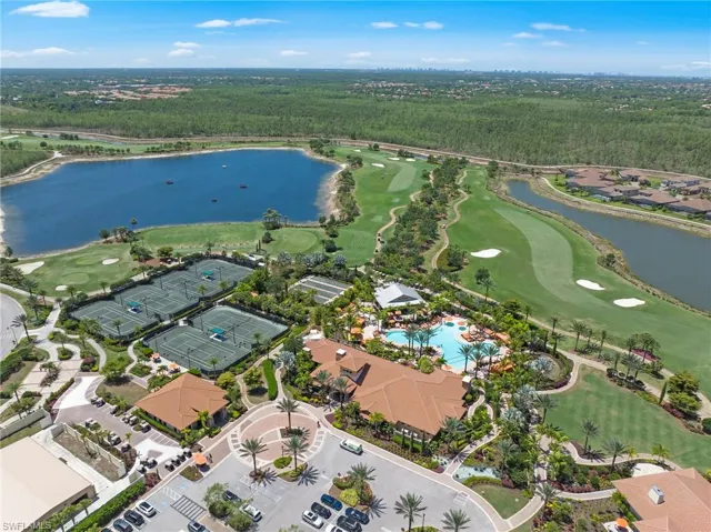 Expansive aerial view showcasing a large aquatic feature, multiple tennis courts, and a golf course