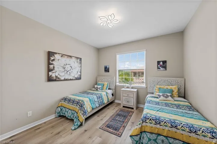 Spacious room featuring wood-finish flooring, light-toned walls, and a contemporary ceiling light fixture