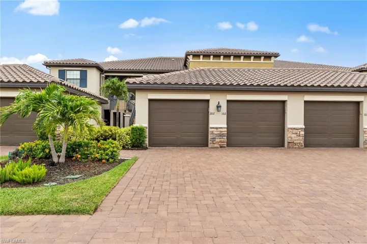 Multi-unit building featuring a tiled roof, stucco exterior, and multiple brown garage doors