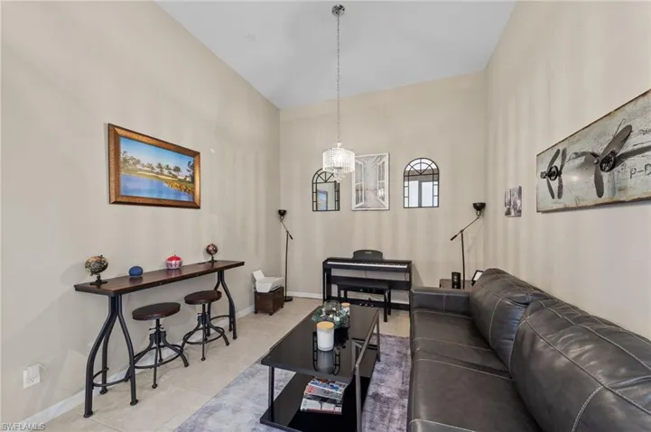 Vaulted ceiling room featuring neutral wall tones and tile flooring