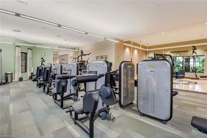 Fitness center featuring a variety of exercise equipment, patterned carpet flooring, and integrated ceiling lighting
