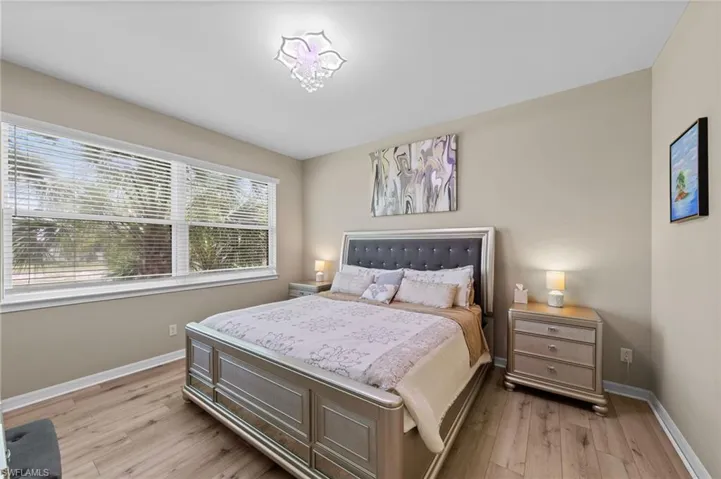 Bedroom featuring wood-finish flooring, neutral wall tones, and a large window with horizontal blinds