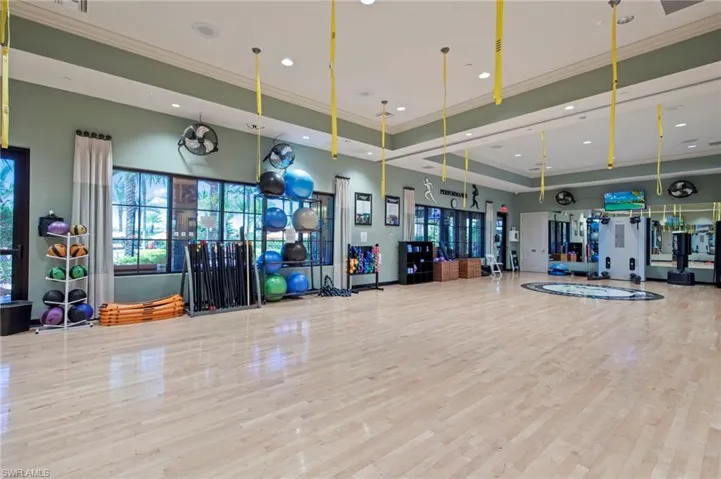 Spacious fitness studio featuring wood-finish flooring, recessed lighting, large windows, mirrored walls, and built-in wall-mounted fans
