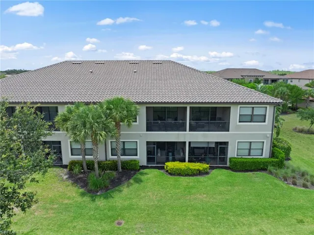 Spacious multi-story exterior with a tiled roof, screened balconies, and a manicured lawn