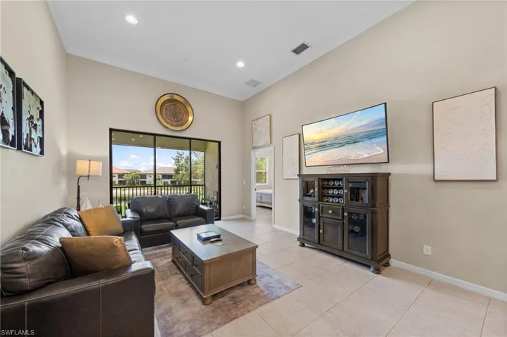 Spacious living area featuring high vaulted ceilings with recessed lighting, tile flooring, and crown molding