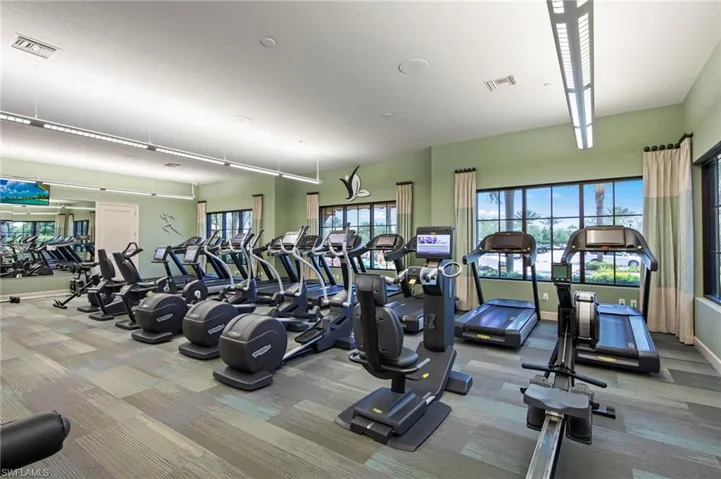 Fitness center with a variety of exercise equipment, large windows, recessed lighting, and a mirrored wall