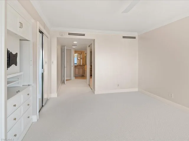 Unfurnished room with ceiling fan, light colored carpet, and crown molding