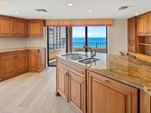 Kitchen with light hardwood / wood-style flooring, light stone counters, a water view, and sink