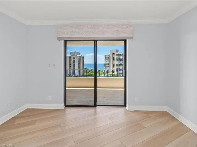 Empty room with light hardwood / wood-style floors and ornamental molding