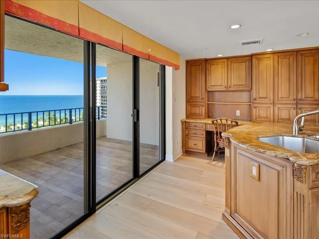 Kitchen featuring light stone counters, light hardwood / wood-style floors, sink, and a water view