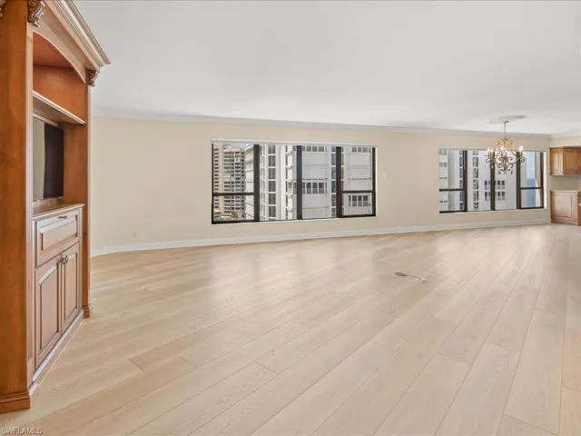 Unfurnished living room with light hardwood / wood-style flooring, crown molding, and a chandelier
