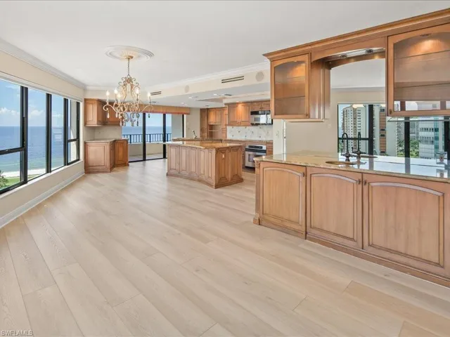 Kitchen with a water view, kitchen peninsula, decorative light fixtures, sink, and a chandelier