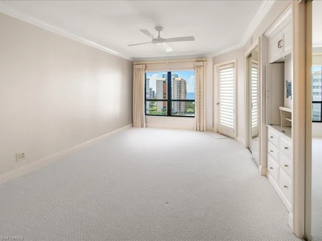 Carpeted empty room featuring ornamental molding and ceiling fan