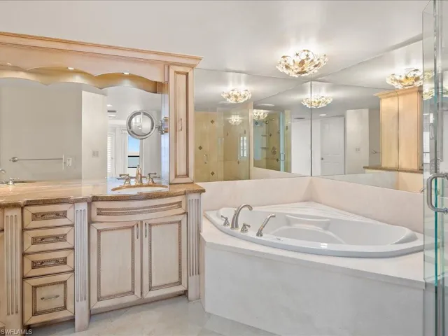 Bathroom featuring vanity, plus walk in shower, and a notable chandelier