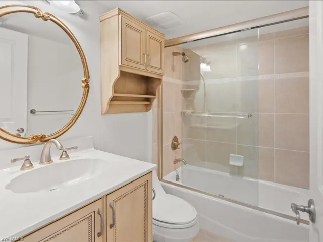 Full bathroom featuring bath / shower combo with glass door, vanity, and toilet