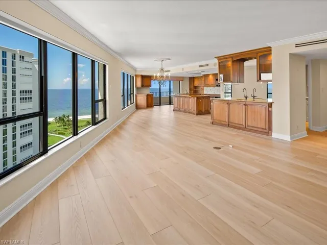 Unfurnished living room with a notable chandelier, plenty of natural light, ornamental molding, and a water view
