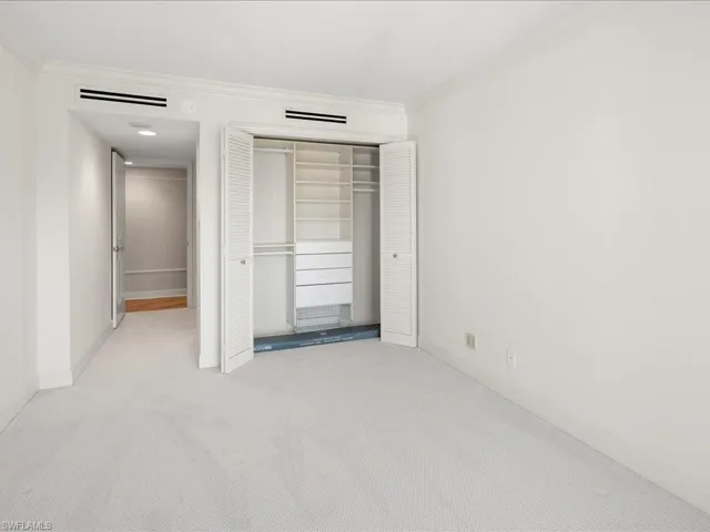 Unfurnished bedroom featuring ornamental molding, a closet, and light carpet