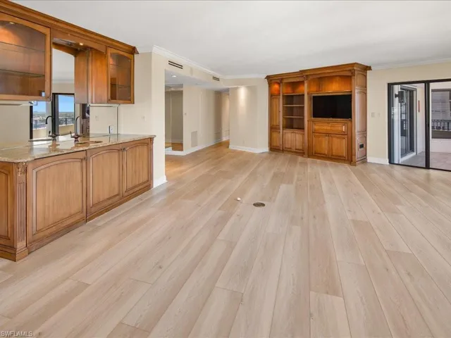 Kitchen with light stone counters, light hardwood / wood-style flooring, crown molding, and kitchen peninsula
