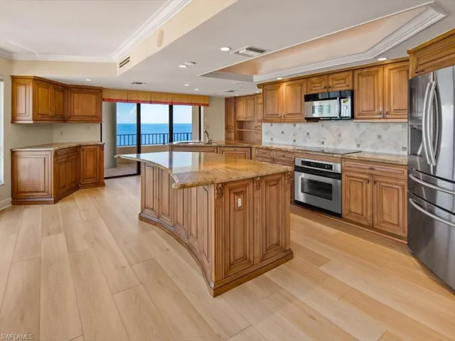 Kitchen featuring light hardwood / wood-style flooring, stainless steel appliances, a raised ceiling, and a center island