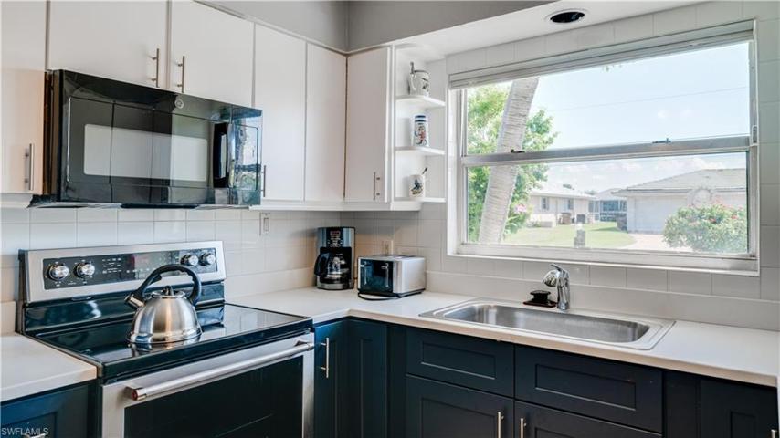 Kitchen has a large window and a lot of cabinets.