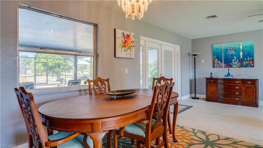 Dining area looking out to living area with French Doors leading to large lanai, pool, and canal.