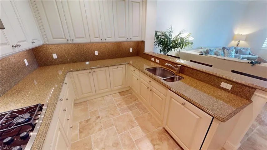 Kitchen featuring sink, backsplash, gas cooktop, and light stone countertops