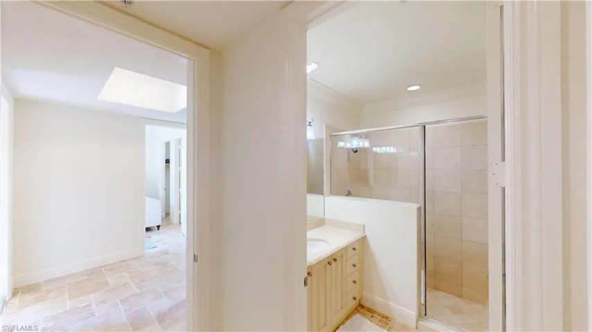 Bathroom featuring vanity, ornamental molding, an enclosed shower, and a skylight