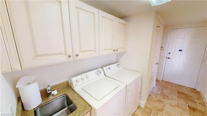 Clothes washing area with cabinets, sink, and independent washer and dryer