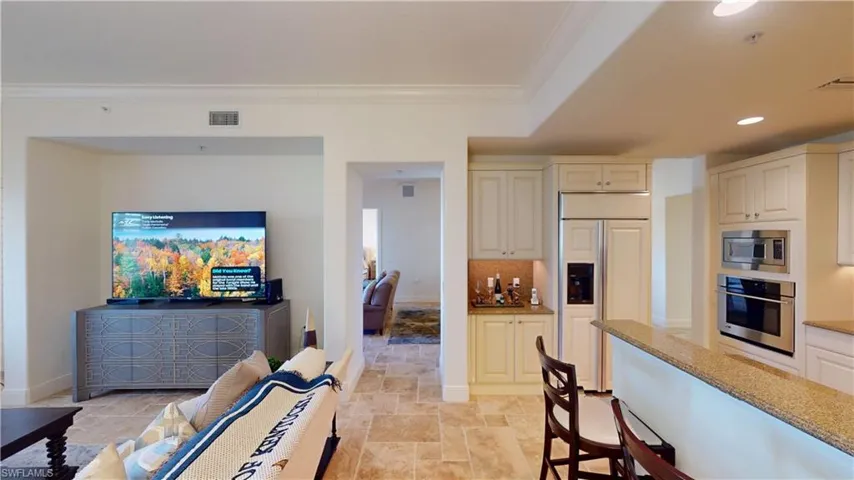 Kitchen with ornamental molding, built in appliances, light stone counters, and decorative backsplash
