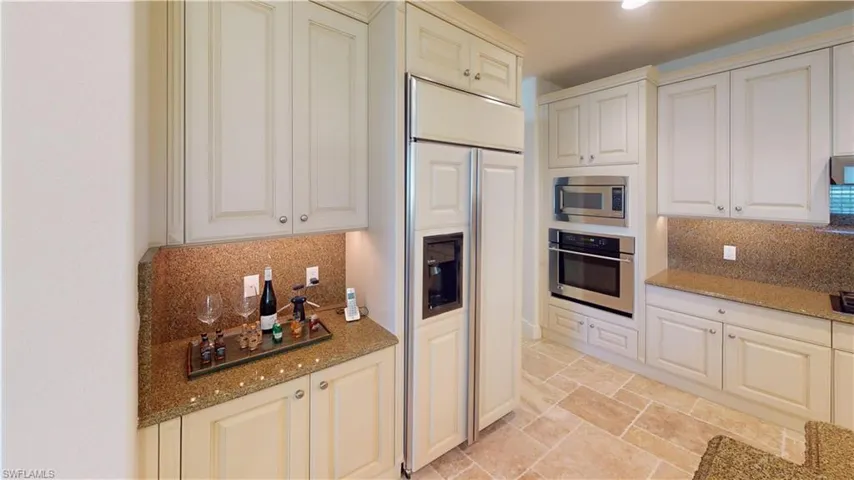 Kitchen with built in appliances, light stone countertops, and backsplash