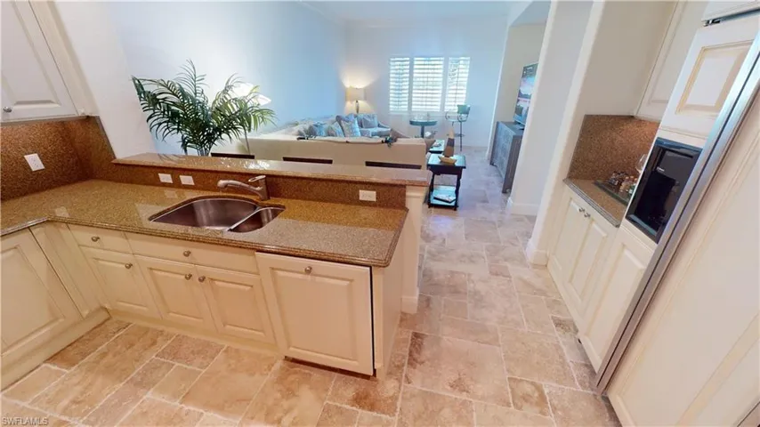 Kitchen featuring sink, light stone counters, crown molding, tasteful backsplash, and kitchen peninsula