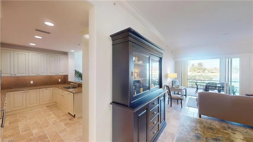 Kitchen with ornamental molding, light stone countertops, sink, and decorative backsplash
