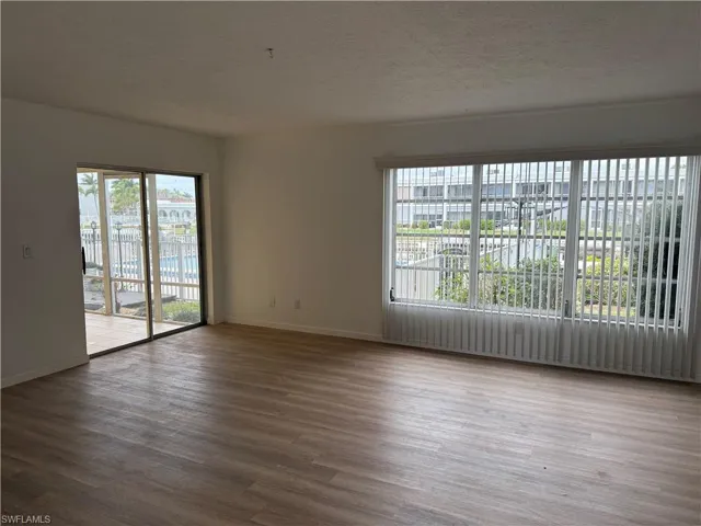 Unfurnished room featuring plenty of natural light, a textured ceiling, and dark wood-style floors